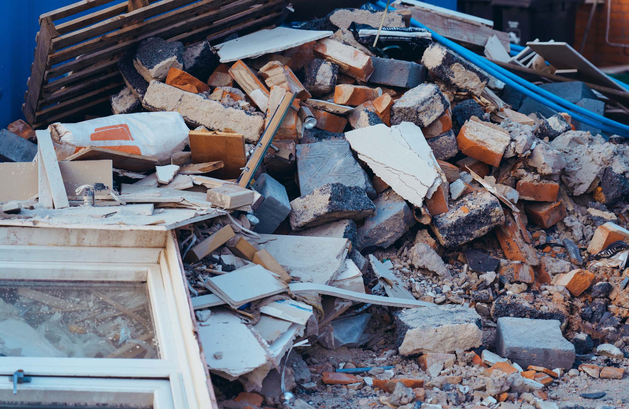 A pile of construction waste near private house. Building rubble, bricks, stones. Junk, garbage piled up near the building. Street scene. Recycling industry, rubbish removal and collection service
